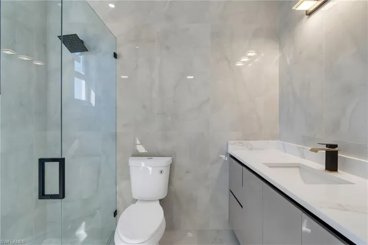 Bathroom featuring tile walls, vanity, and a marble finish shower
