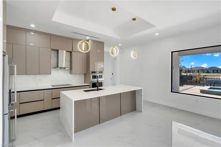 Kitchen with modern cabinets, stainless steel appliances, gray cabinets, a tray ceiling, and decorative light fixtures