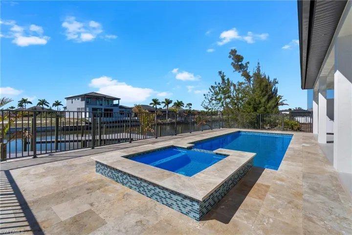 Relaxing pool / spa with a patio area, a fenced backyard, and a water view
