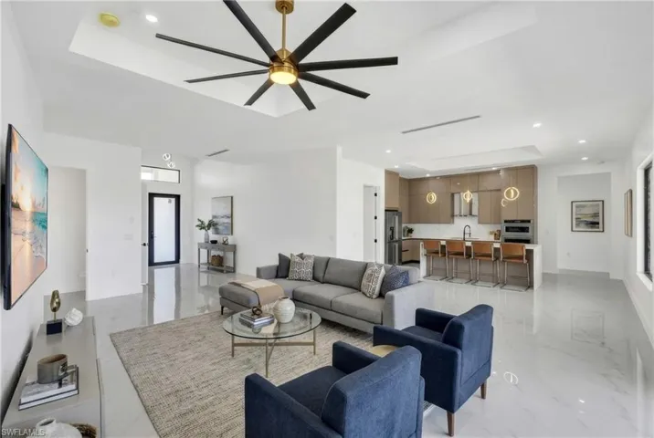 Living area with recessed lighting, a tray ceiling, and ceiling fan