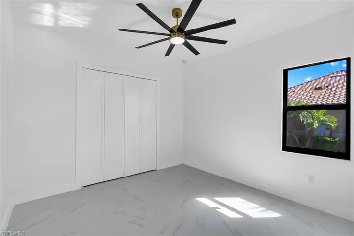 Unfurnished bedroom with light marble finish floors, a ceiling fan, and a closet