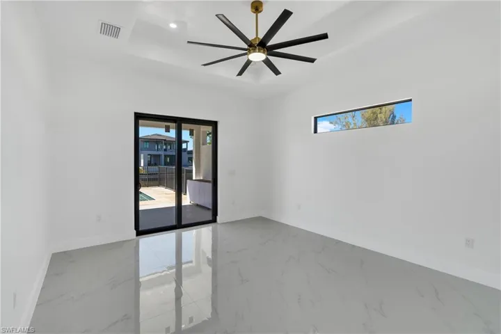 Empty room featuring light marble finish floors and a ceiling fan