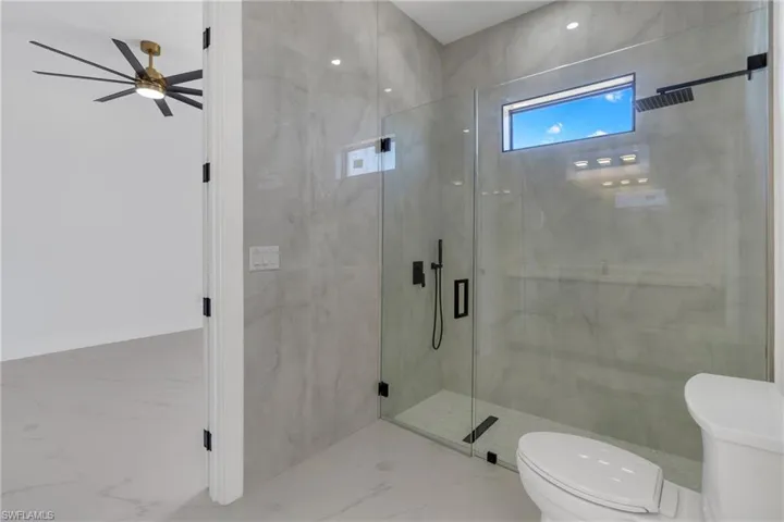 Full bath with toilet and a marble finish shower