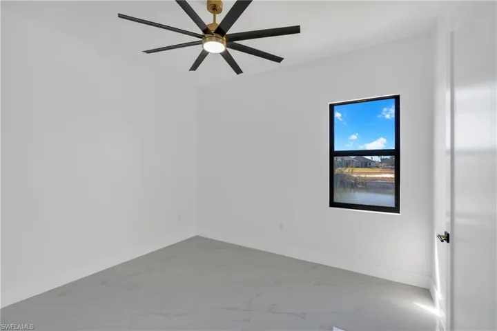 Empty room featuring marble look tile flooring and a ceiling fan