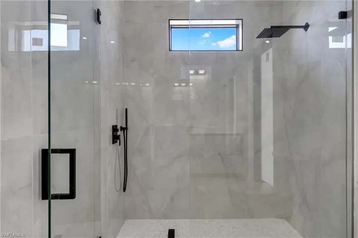 Bathroom with a marble finish shower and healthy amount of natural light