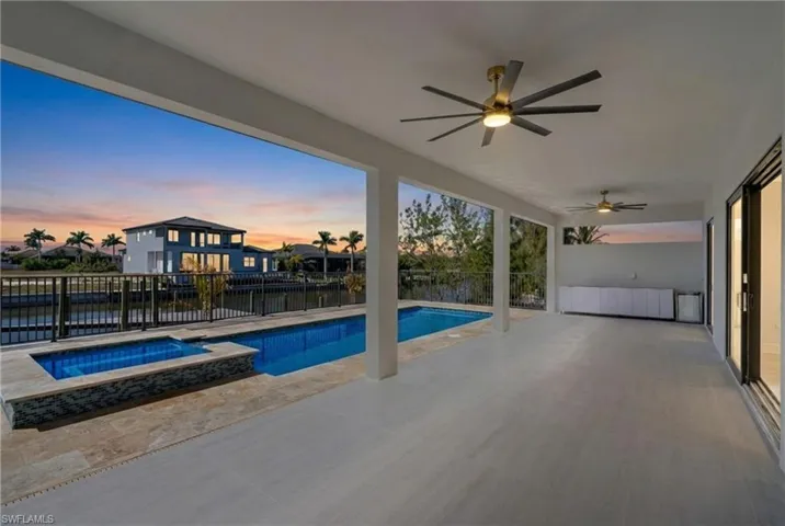 Pool at dusk featuring a patio area, a pool with connected hot tub, and a fenced backyard