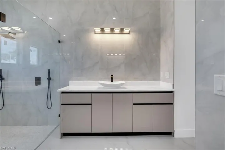 Full bath with vanity, a marble finish shower, and tile walls