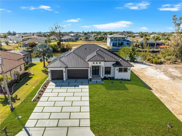 Modern farmhouse with a garage, concrete driveway, a front yard, stucco siding, and a metal roof