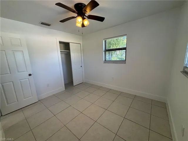 Unfurnished bedroom featuring light tile patterned floors, a closet, and a ceiling fan