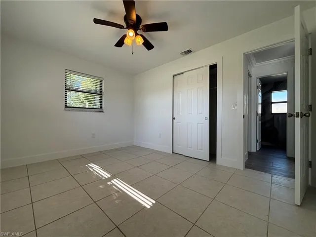 Unfurnished bedroom featuring light tile patterned floors, a closet, and a ceiling fan