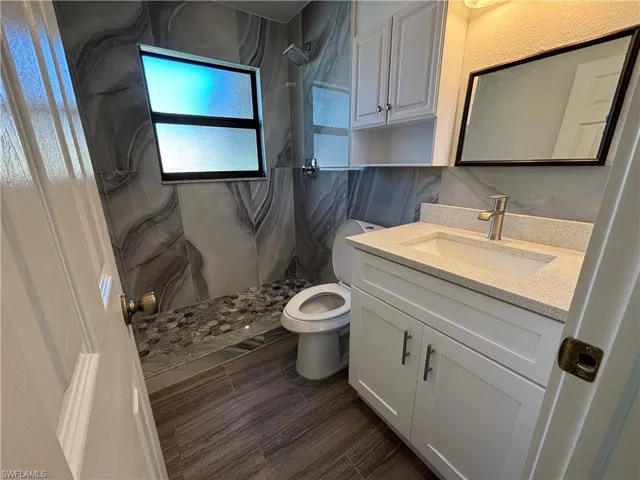 Bathroom with vanity and a marble finish shower