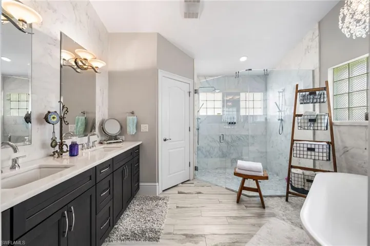 Bathroom featuring a shower with shower door, tile patterned floors, double sink vanity, and a chandelier