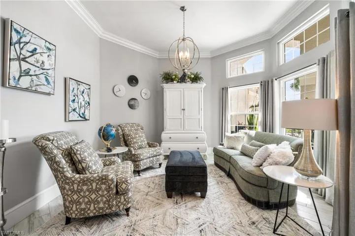 Living room featuring a wealth of natural light, crown molding, and a chandelier