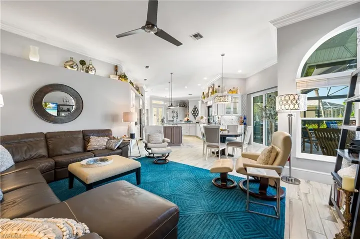 Living room with crown molding, ceiling fan with notable chandelier, and light hardwood / wood-style floors