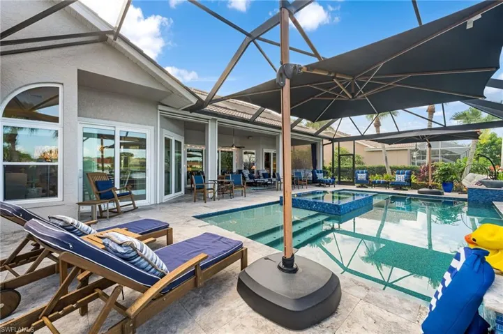 View of swimming pool featuring a patio area, an in ground hot tub, and glass enclosure