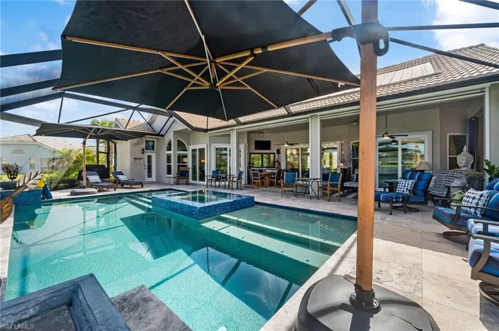 View of pool with an in ground hot tub, a patio, and glass enclosure