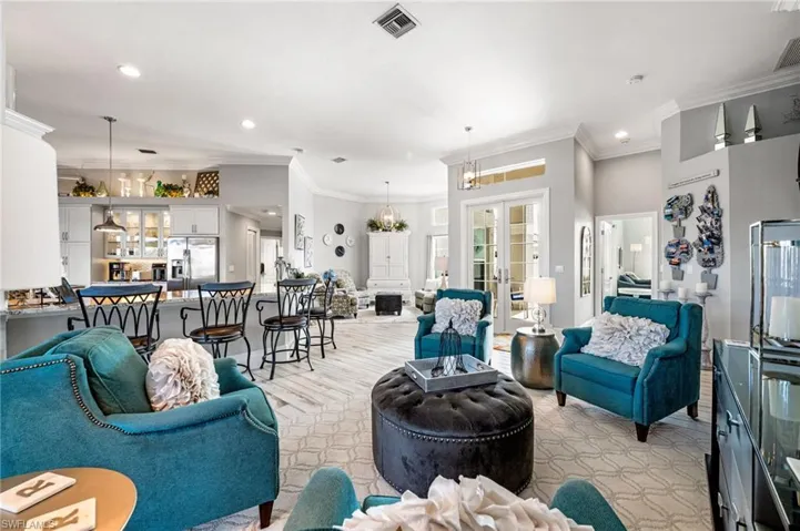 Living room featuring crown molding, a notable chandelier, and french doors