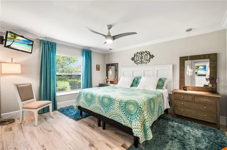 Bedroom featuring ceiling fan, wood-type flooring, and ornamental molding
