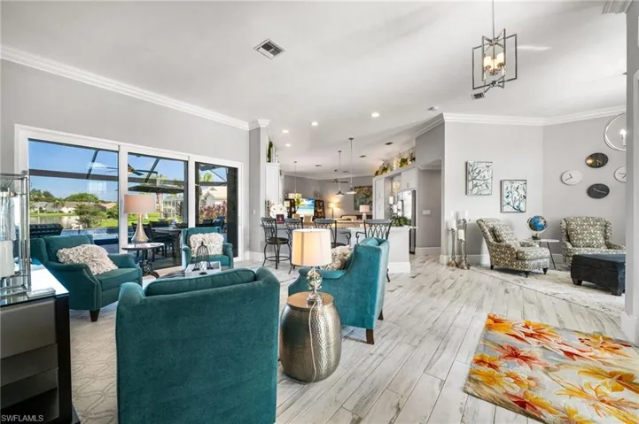 Living room featuring ornamental molding, an inviting chandelier, and light wood-type flooring