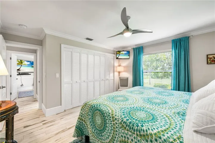 Bedroom with ornamental molding, ceiling fan, and light wood-type flooring