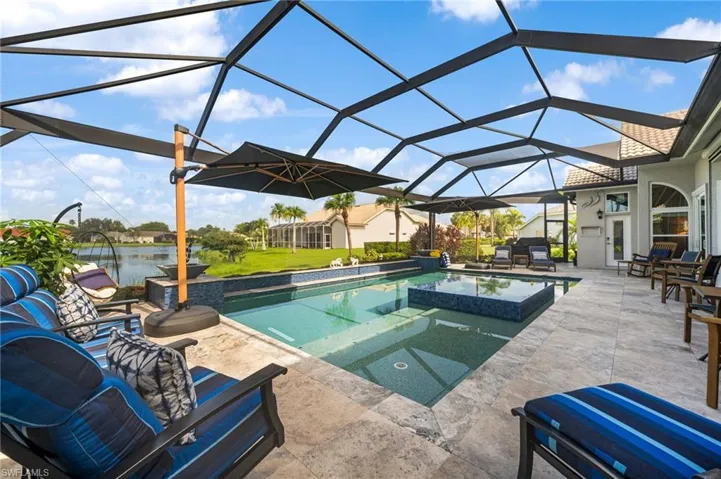 View of pool with an in ground hot tub, a lanai, a water view, and a patio area