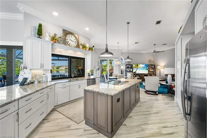 Kitchen with appliances with stainless steel finishes, tasteful backsplash, a kitchen island, white cabinetry, and ceiling fan