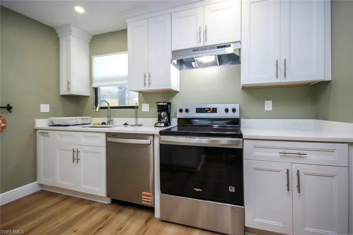 Kitchen featuring white cabinets, light countertops, stainless steel appliances, under cabinet range hood, and a sink