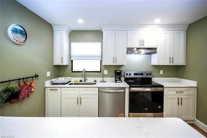 Kitchen with white cabinets, stainless steel appliances, recessed lighting, under cabinet range hood, and a sink