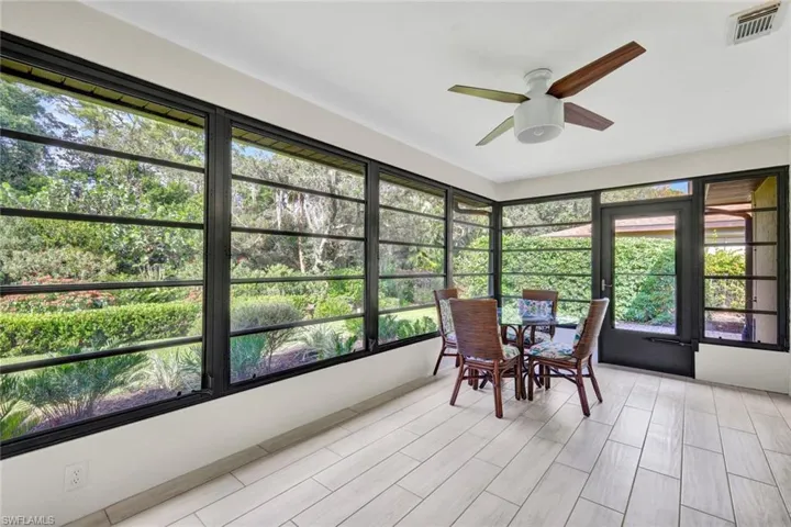 This view of the lanai showcases the great light offered from all the windows in this space.  It is shown partially furnished and has a ceiling fan.