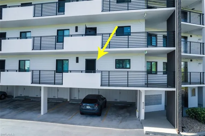 View of apartment building / complex featuring covered parking