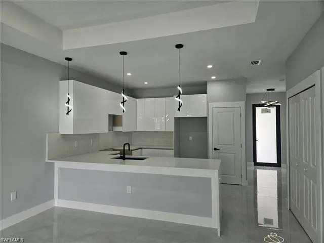 Kitchen with a sink, white cabinetry, modern cabinets, backsplash, and a peninsula