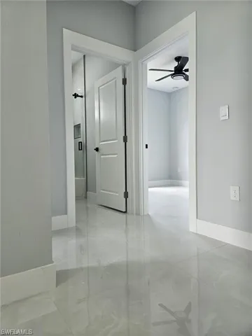 Hallway with baseboards and light marble finish flooring