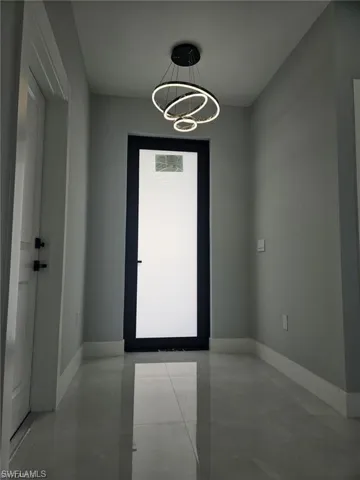 Unfurnished room with a chandelier and baseboards