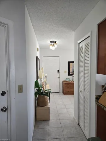 Hallway featuring light tile patterned floors and a textured ceiling