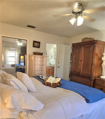 Bedroom with a textured ceiling, a closet, ceiling fan, and ensuite bathroom