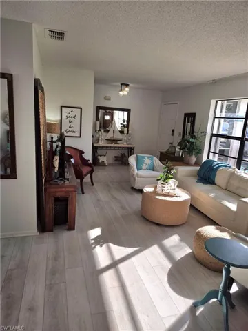 Living room featuring a textured ceiling and light hardwood / wood-style flooring