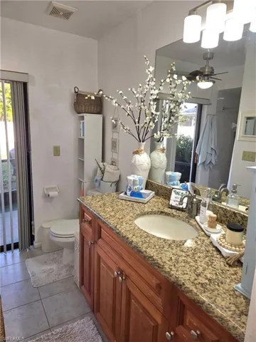 Bathroom with vanity, tile patterned floors, ceiling fan, and toilet