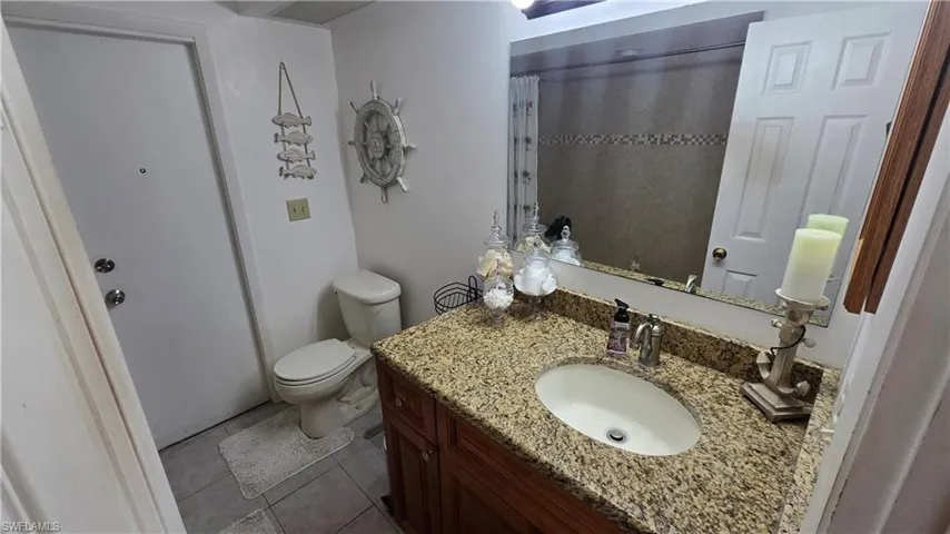 Bathroom featuring tile patterned flooring, vanity, toilet, and walk in shower