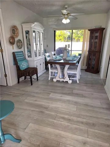 Dining space with ceiling fan, a textured ceiling, and light hardwood / wood-style flooring