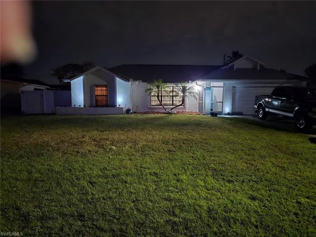 View of front of property featuring a lawn and a garage