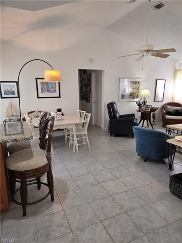 Tiled living room featuring lofted ceiling, ceiling fan, and a textured ceiling