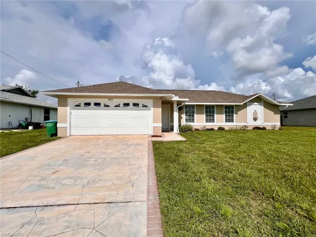 Single story home featuring stucco siding, a garage, decorative driveway, and a front lawn