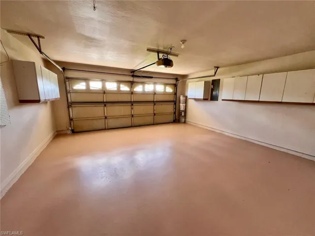 Garage featuring baseboards and a garage door opener