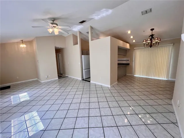 Unfurnished living room with a chandelier, light tile patterned floors, lofted ceiling, ceiling fan, and recessed lighting