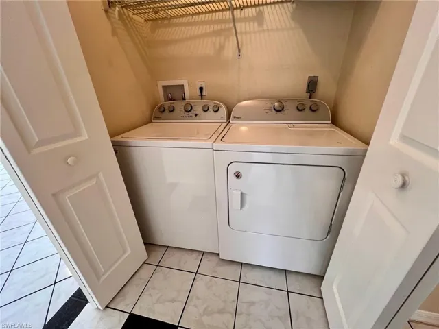Laundry area with washer and clothes dryer and light tile patterned floors