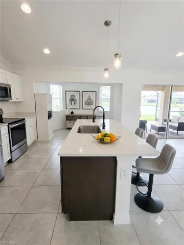 Modern kitchen and dining area featuring a spacious island with waterfall-edge countertop, pendant lighting, and integrated seating