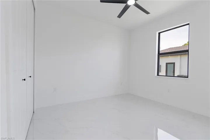 Unfurnished room featuring baseboards, marble finish floor, and ceiling fan