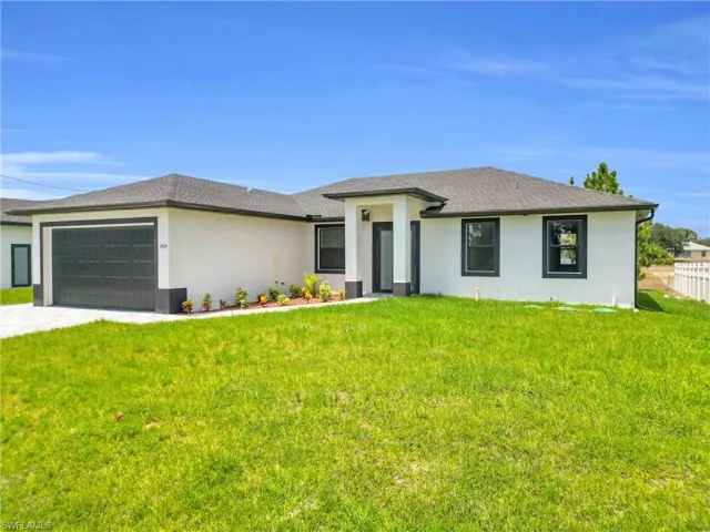 Prairie-style home with an attached garage, driveway, stucco siding, and a front yard