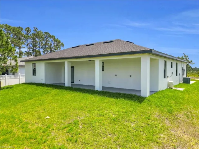 Back of house featuring central AC, fence, stucco siding, a shingled roof, and a yard