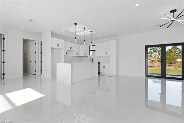 Unfurnished living room with a sink, french doors, marble finish floor, recessed lighting, and visible vents